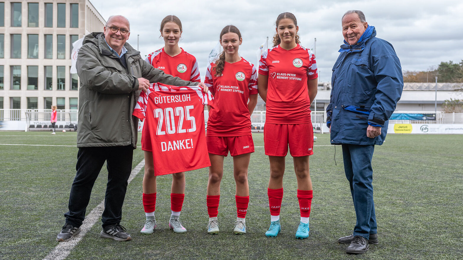 Klaus-Peter Reinert (rechts) erhält von FSV-Geschäftsführer Michael Horstkötter im Beisein der U17-Spielerinnen Leandra Stienhans, Betty Meier und Mara Nölle ein Danke-Trikot. (Foto: Boris Kessler / FSV Gütersloh 2009)